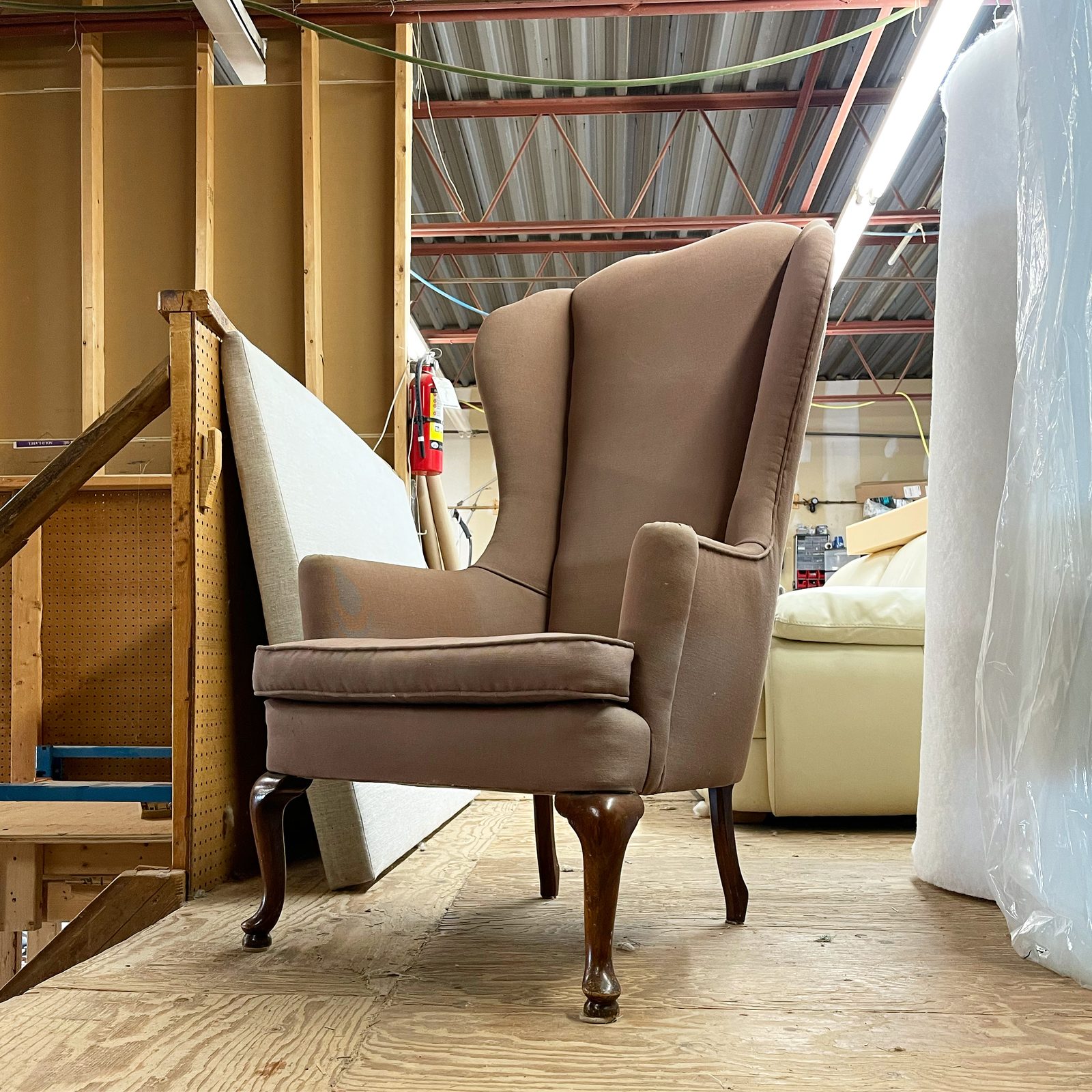 Wing chair stripped to its bare frame on the workbench