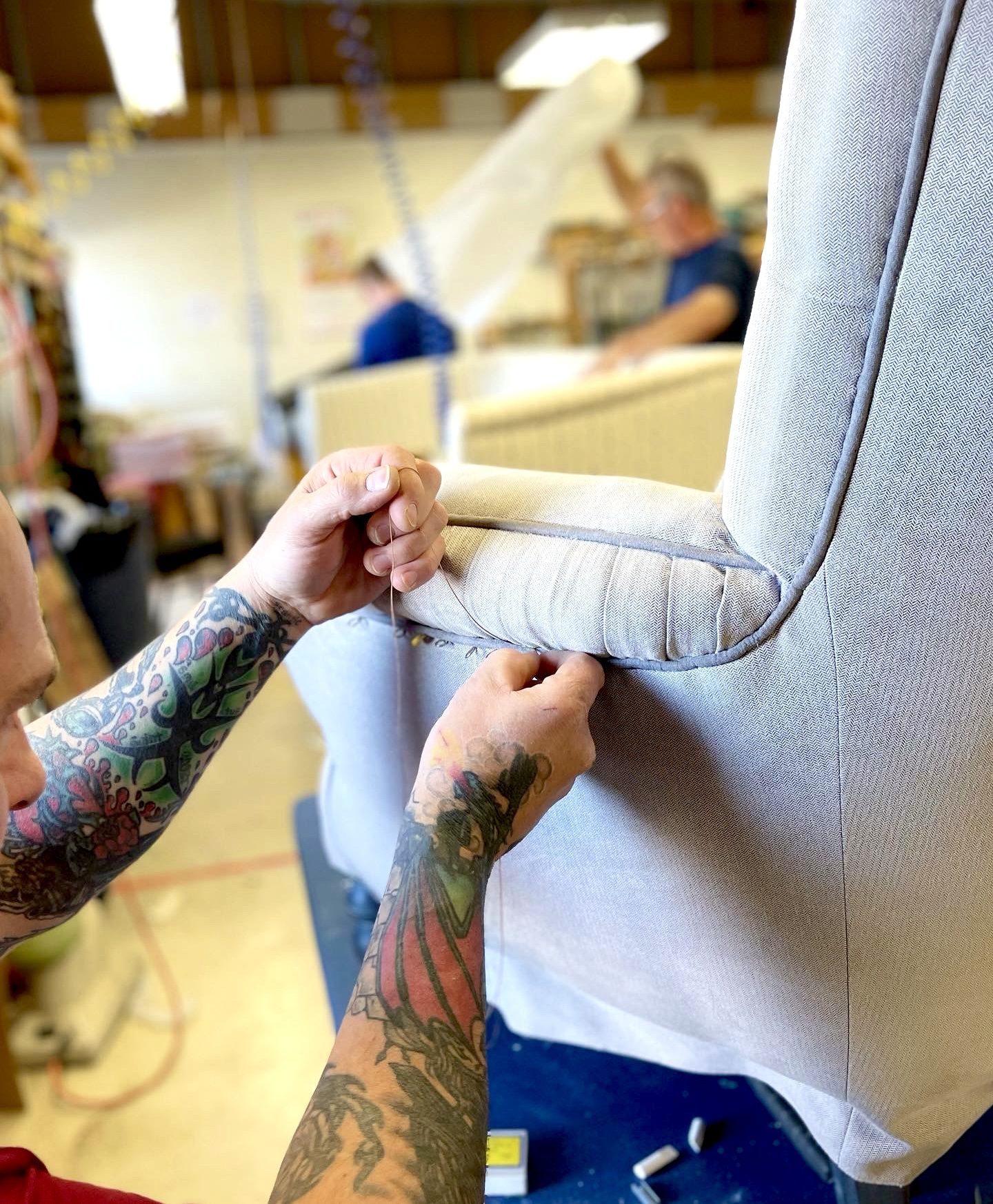 Hands stitching the arm of a wing chair